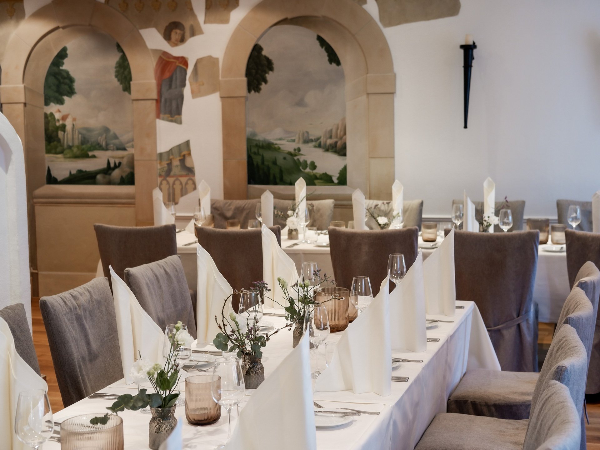 Hochzeitslocation Oberpfalz mit Hotel & Festsaal Fein gedeckter Speisesaal mit weißen Servietten und malerischen Wandgemälden