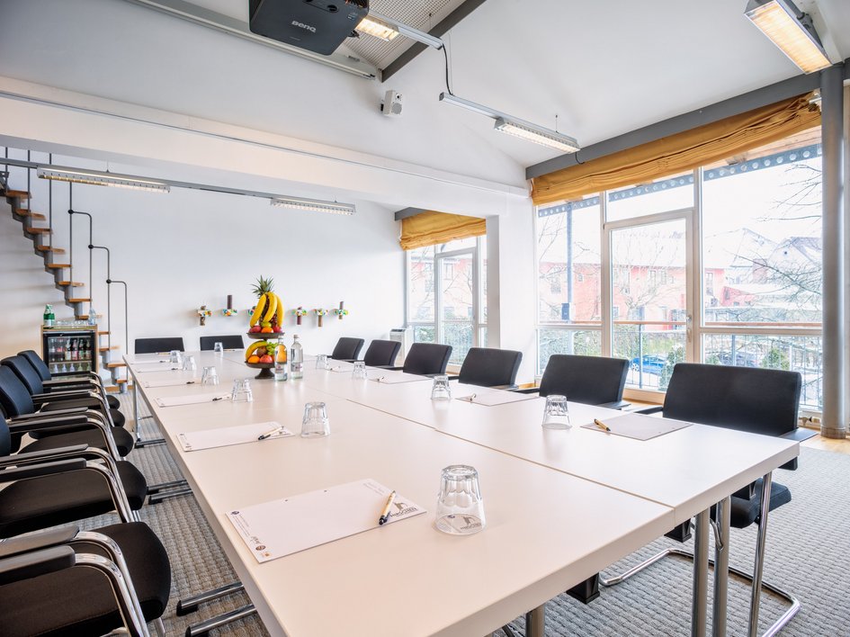 Leistungen und Preise für Tagungen und Konferenzen Helles, modern eingerichtetes Besprechungszimmer mit Tischen, Stühlen und Obstkorb