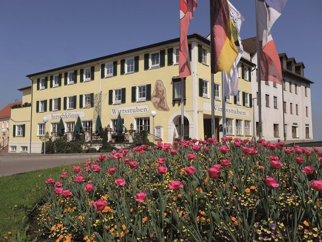 Romantik Hotel Hirschen: picture gallery Yellow inn with green windows, red tulips in front and flags waving in the wind