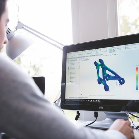 Looking for a hotel with bike rental in Bavaria? Person working on 3D modeling and simulation on computer at desk