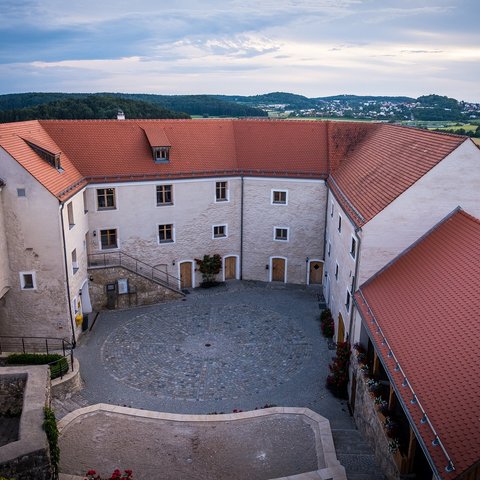 Hotels in Regensburg und Umgebung: kultur-trächtig! Innenhof eines historischen Gebäudes mit roten Ziegeldächern und Aussicht auf Landschaft
