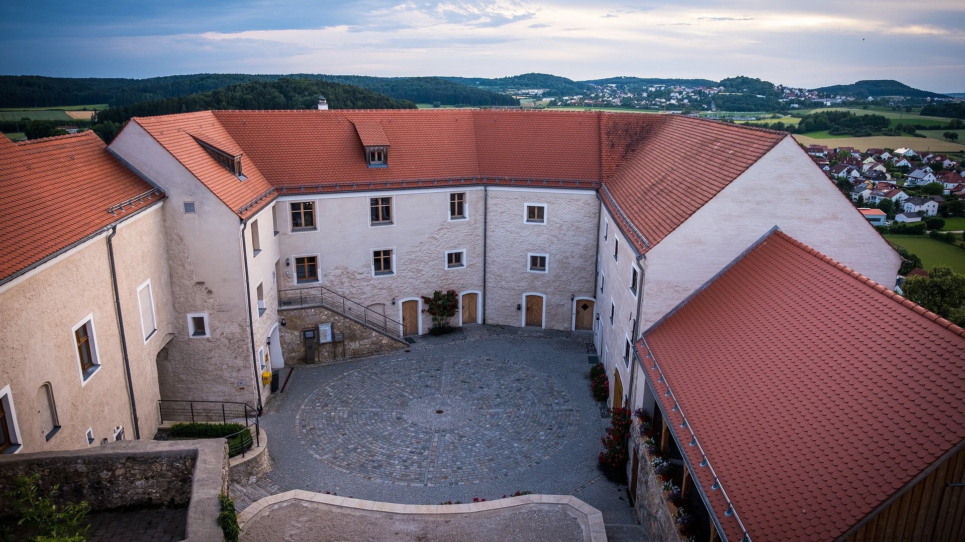 Hotels in Regensburg und Umgebung: kultur-trächtig! Innenhof eines historischen Gebäudes mit roten Ziegeldächern und Aussicht auf Landschaft