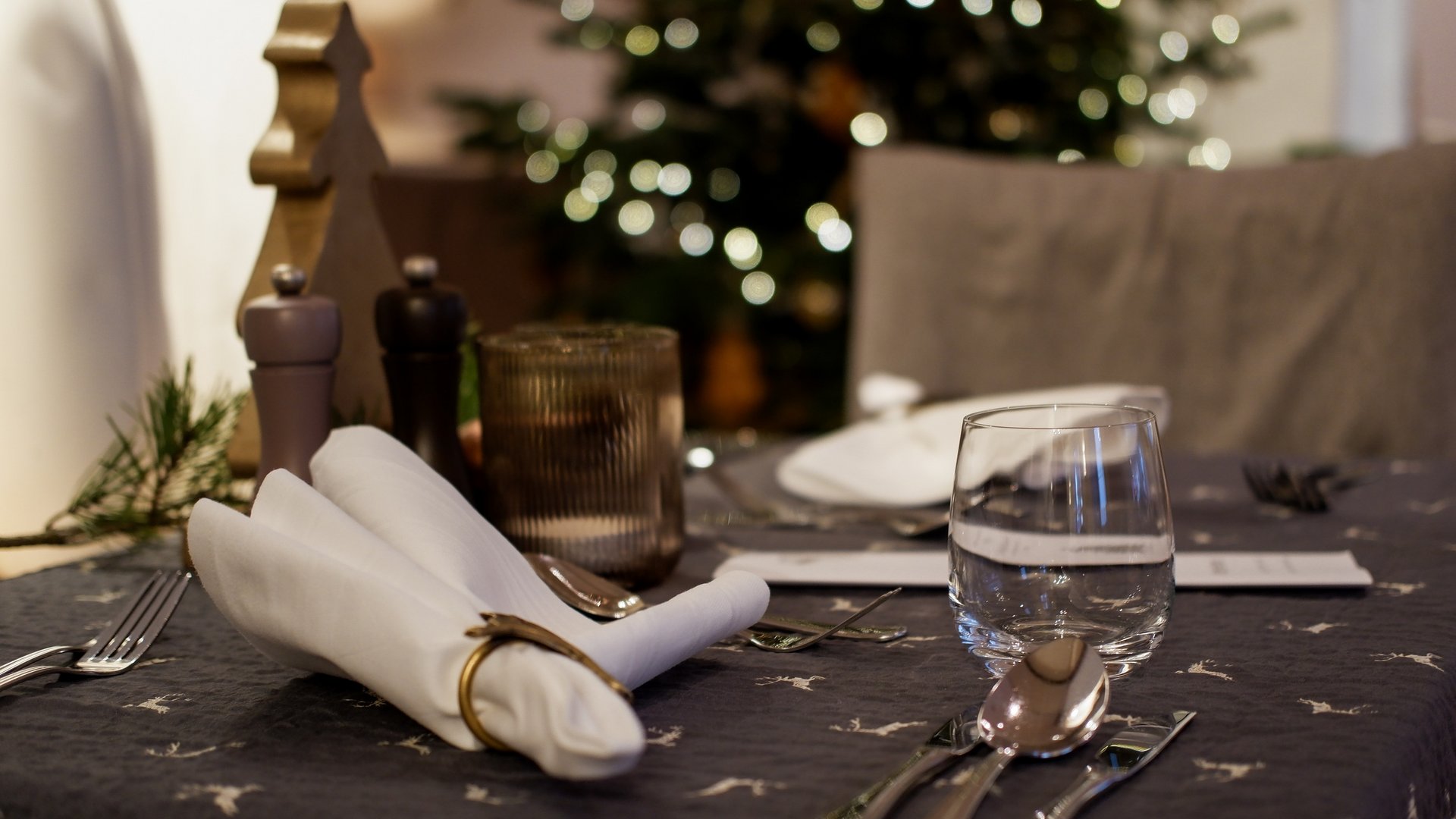 Weihnachtsmenüs 2025 Festlich gedeckter Esstisch mit Serviette, Glas und Besteck vor Weihnachtsbaum