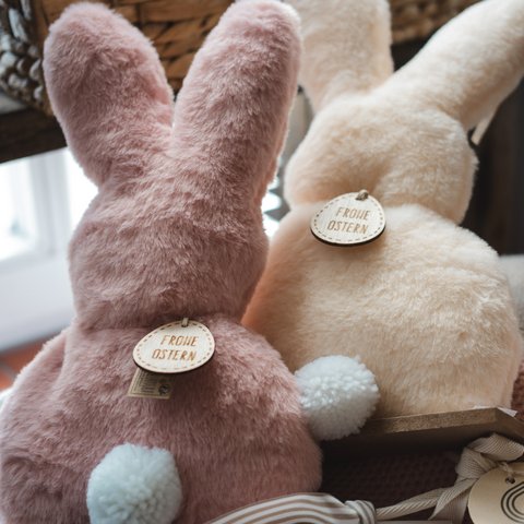 Nachhaltiges Hotel in Bayern mit Hirschenmanufaktur Zwei flauschige Osterhasenplüschtiere mit bunten Pompons und Frohe Ostern Anhänger