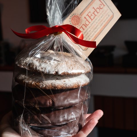 Eco-friendly hotel in Germany with Hirschenmanufaktur Hand holding packaged gingerbread with red ribbon and label
