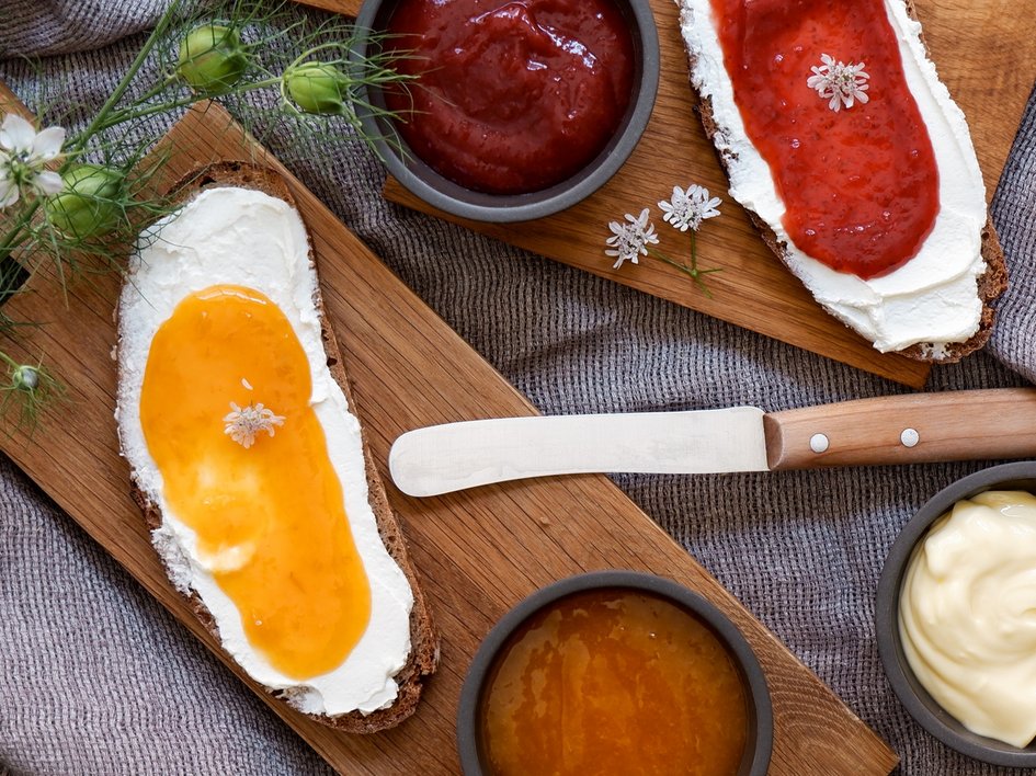 Eco-friendly hotel in Germany with Hirschenmanufaktur Bread with cream cheese and jam on wooden boards with knife and bowls of spreads