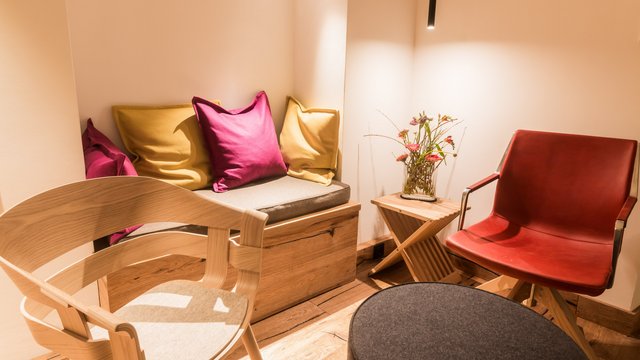 Ferienwohnung in der Oberpfalz gesucht? Gemütliche Sitzecke mit bunten Kissen, Holzmöbeln und roten Lederstuhl