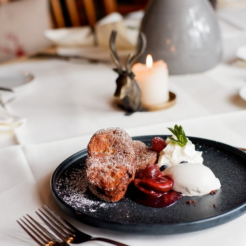 Guesthouse in Parsberg: A salute to great taste Dessert with powdered sugar, fruits, cream, and ice cream on a black plate