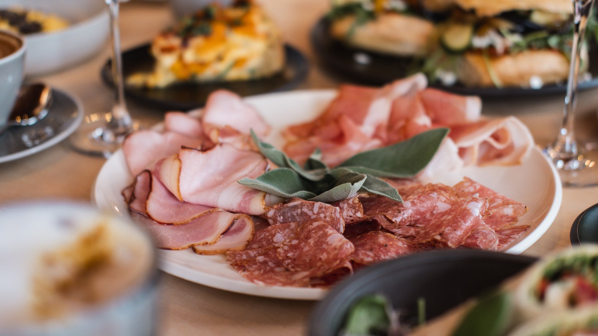 Brunch - das Langschläferfrühstück Verschiedene Aufschnittsorten auf einem Teller mit Salbeiblättern
