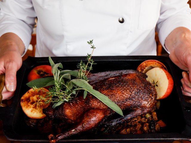 Romantik Hotel Hirschen: Bildergalerie Ganze gebratene Ente mit Kräutern und Apfelscheiben auf einer Servierplatte