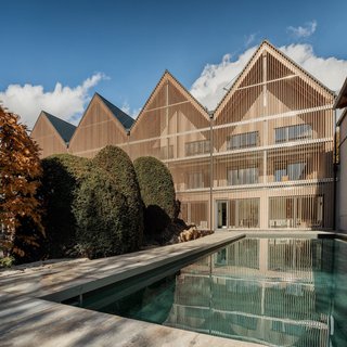 Regensburger Christkindlmarkt Modernes Gebäude mit Holzfassade und Pool im Vordergrund bei sonnigem Wetter