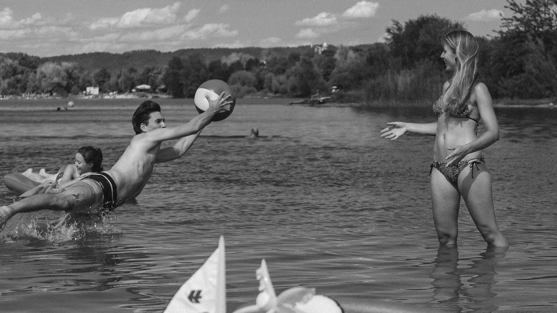 Badeseen Junge Leute spielen mit Ball im Wasser an einem Seeufer