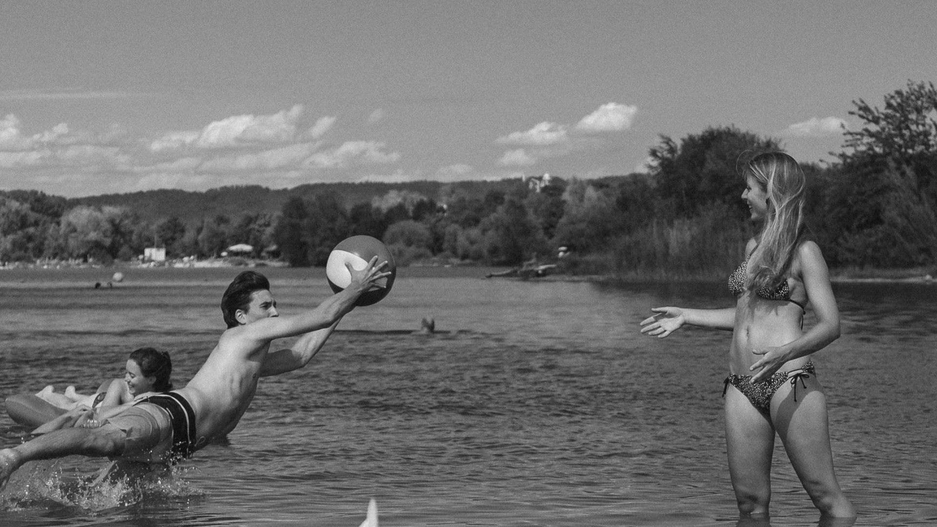 Badeseen Junge Leute spielen mit Ball im Wasser an einem Seeufer