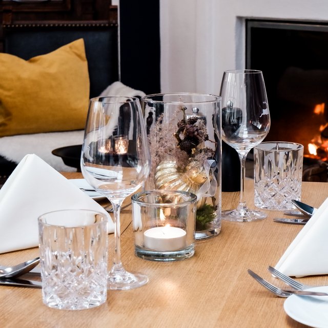 Romantik Hotel Hirschen: Kulinarik eingerichteter tisch mit weißen servietten und glaswaren vor einem kaminfeuer