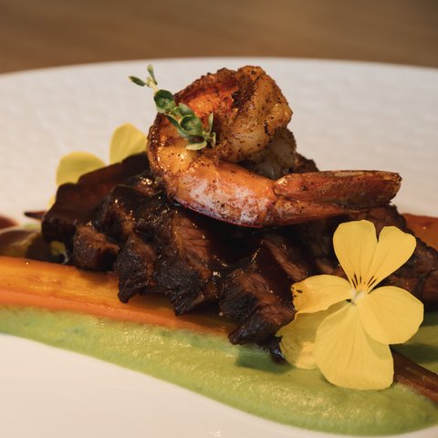 Restaurant in Parsberg: Gourmet genießen Garnelen auf Fleisch mit Karotte, grüner Sauce und essbaren Blüten.