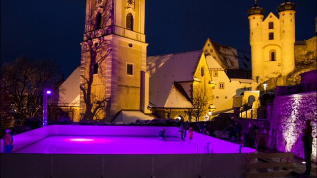 Romantik Hotel Hirschen: Blog Eisbahn mit lila Beleuchtung vor historischen Gebäuden bei Nacht