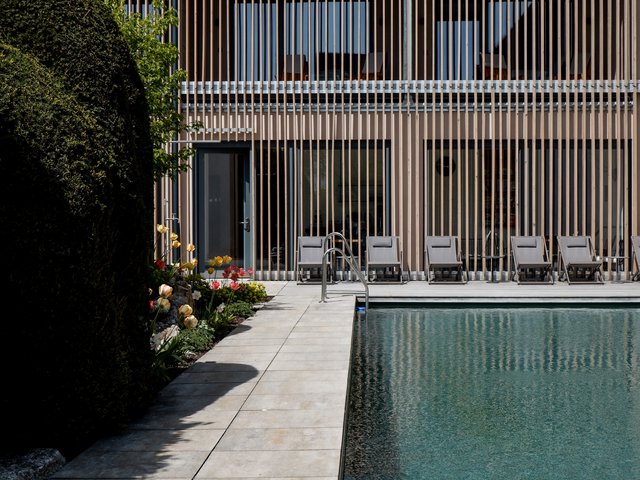 Romantik Hotel Hirschen: Bildergalerie Außenpool mit Liegestühlen vor modernem Gebäude und Frühlingsblumen