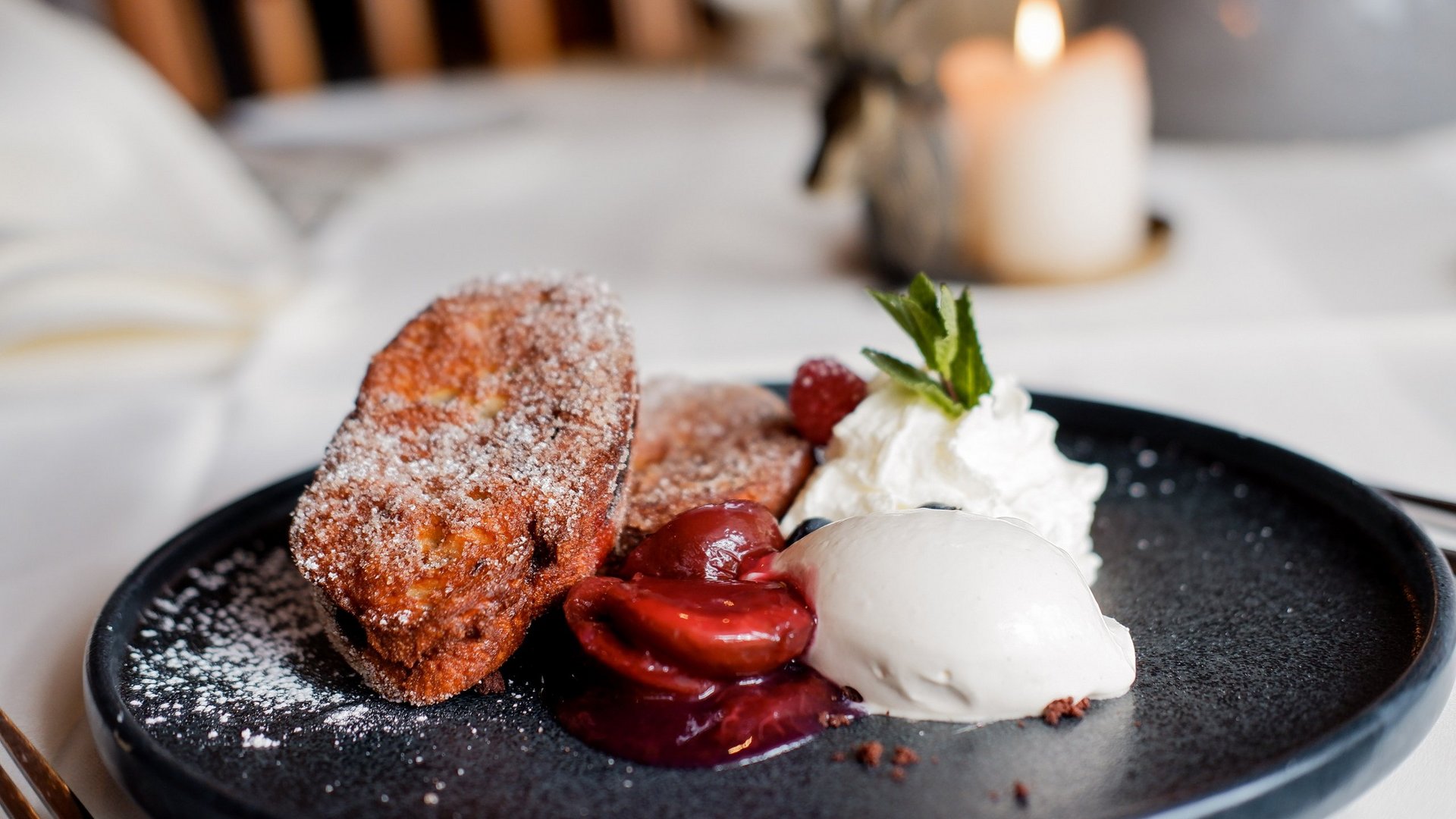 Romantik Hotel Hirschen: cuisine Dessert with fried pastry, cherries, whipped cream and ice cream on black plate
