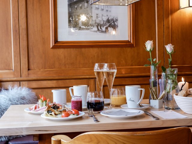 Romantik Hotel Hirschen: Bildergalerie Frühstückstisch mit Getränken, Essen und Blumen in einem Holz-interieur