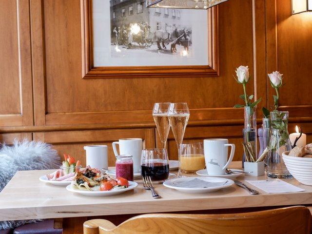 Romantik Hotel Hirschen: Bildergalerie Frühstückstisch mit Getränken, Essen und Blumen in einem Holz-interieur
