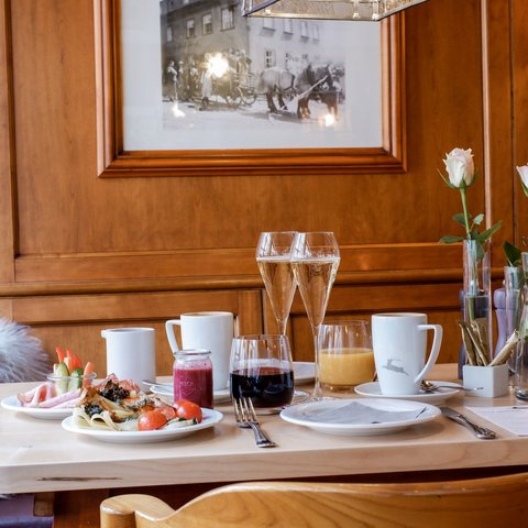 Romantik Hotel Hirschen: Frühstück Frühstückstisch mit Getränken, Essen und Blumen in einem Holz-interieur