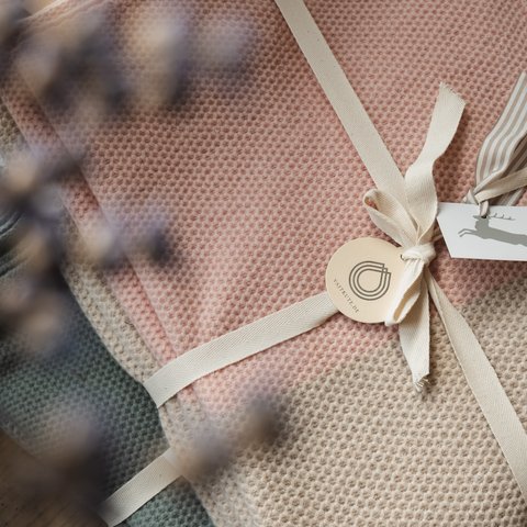 Eco-friendly hotel in Germany with Hirschenmanufaktur Folded waffle knit blankets in various colors with tags attached