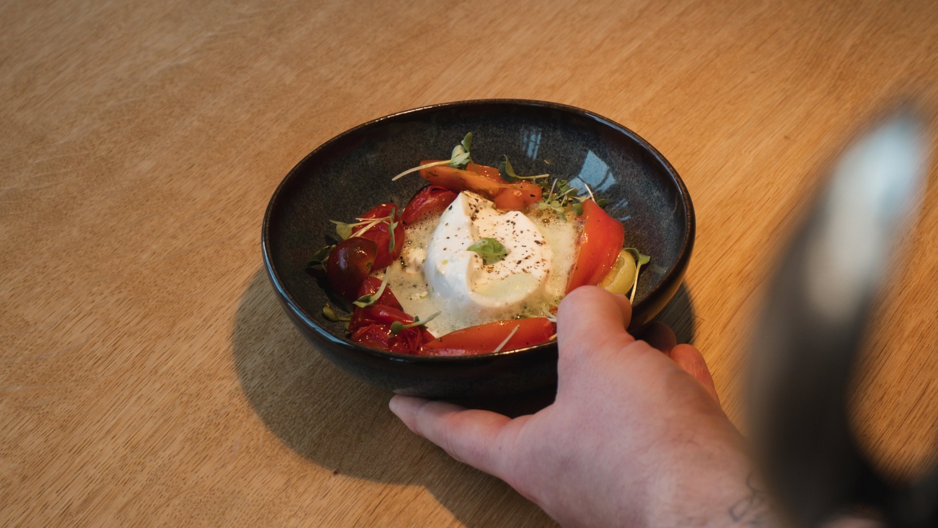 Event calendar 2026 Hand holding bowl with burrata cheese and tomatoes on wooden table