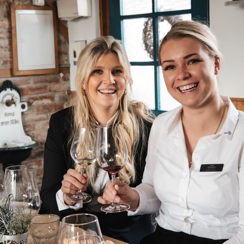 Romantik Hotel Hirschen: Gastgeber & Werte Zwei Frauen stoßen mit Wein in einem gemütlichen Restaurant an