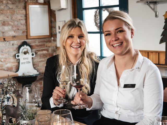 Romantik Hotel Hirschen: Bildergalerie Zwei Frauen stoßen mit Wein in einem gemütlichen Restaurant an