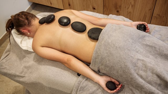 Hotel mit frühem Check-in Person liegt mit heißen Steinen auf dem Rücken bei Hot-Stone-Massage