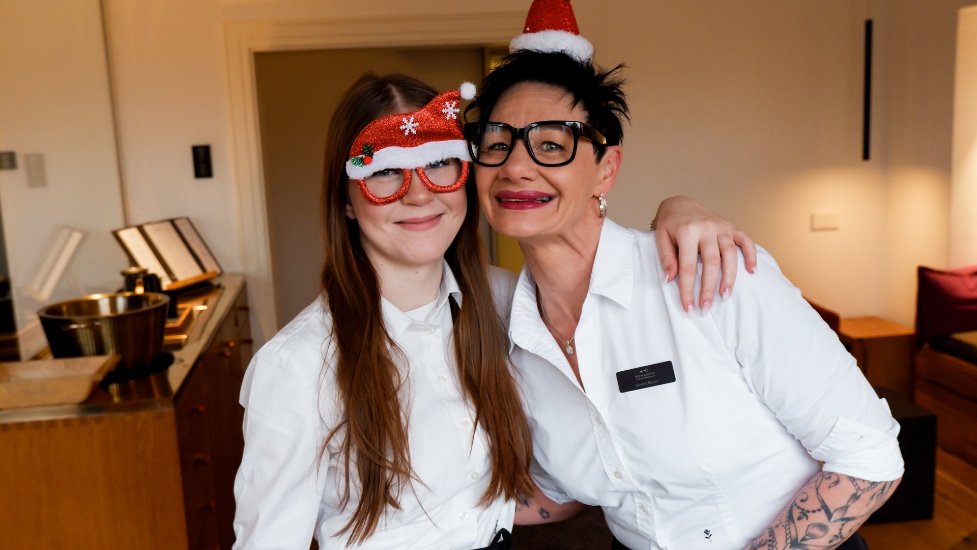 Weihnachtsmenüs 2025 Zwei Frauen mit Weihnachtsmützen feiern fröhlich zusammen