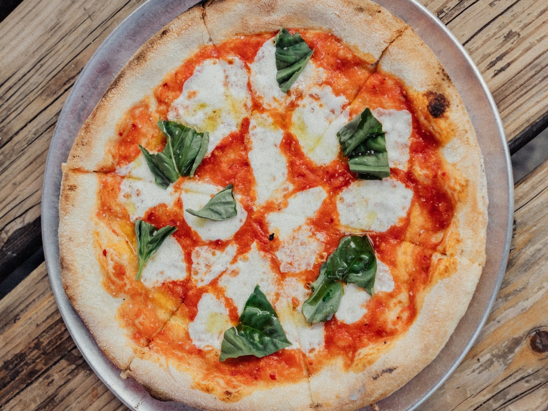 Teambuilding, Firmenevents & Rahmenprogramme Pizza Margherita mit Tomate, Mozzarella und Basilikum auf Holzoberfläche