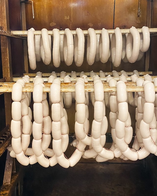 Nachhaltige Hotels in Deutschland gesucht? Weißwürste hängen zum Trocknen in einem Räucherofen