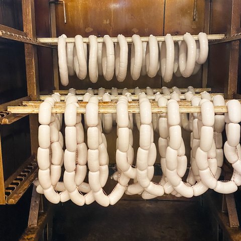 Nachhaltiges Hotel in Bayern mit Hirschenmanufaktur Weißwürste hängen zum Trocknen in einem Räucherofen