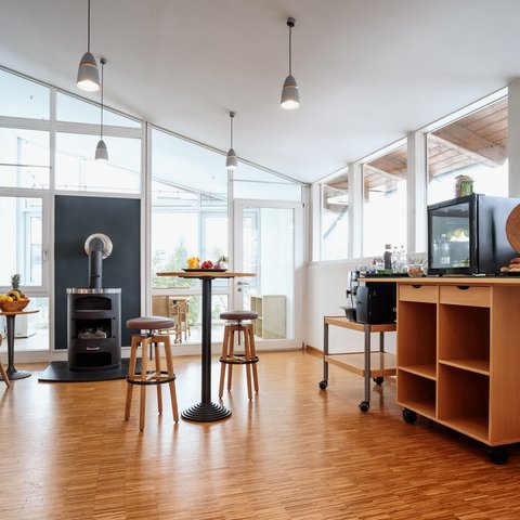 Looking for somewhere for conferences in Bavaria? Bright break room with wooden chair, stove, table, and coffee corner