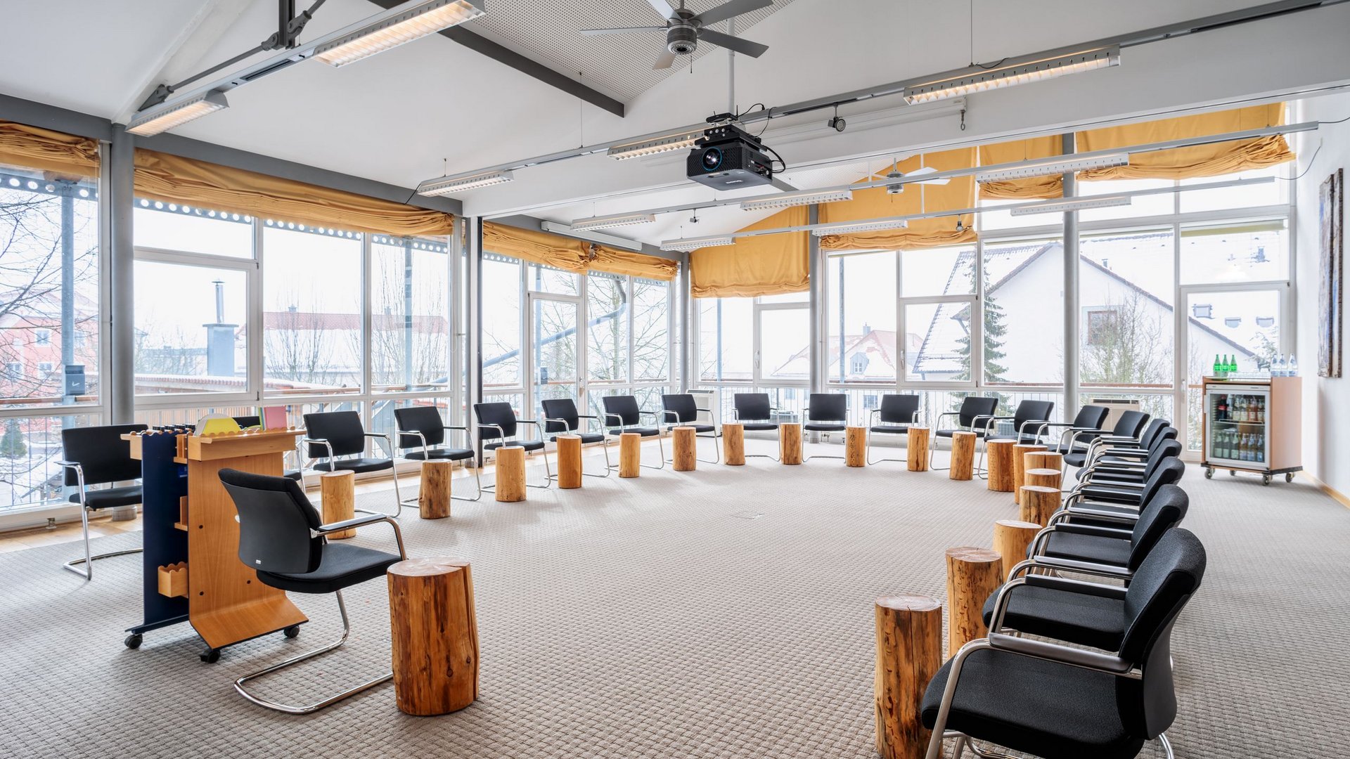 Looking for somewhere for conferences in Bavaria? Large meeting room with circle of chairs and wooden stools near windows in daylight