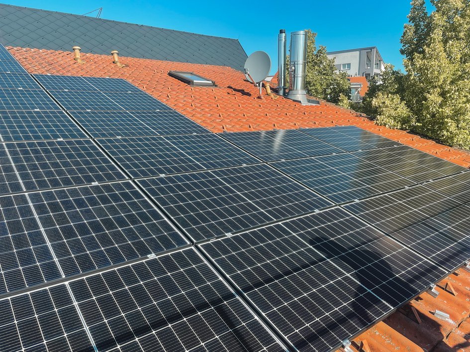 Nachhaltige Hotels in Deutschland gesucht? Solarmodule auf einem roten Ziegeldach bei Sonnenschein