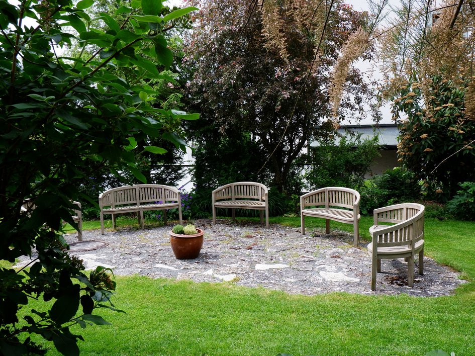 Tagung mit Mehrwert Holzbänke im Kreis in einem Garten mit Rasen und Pflanzen