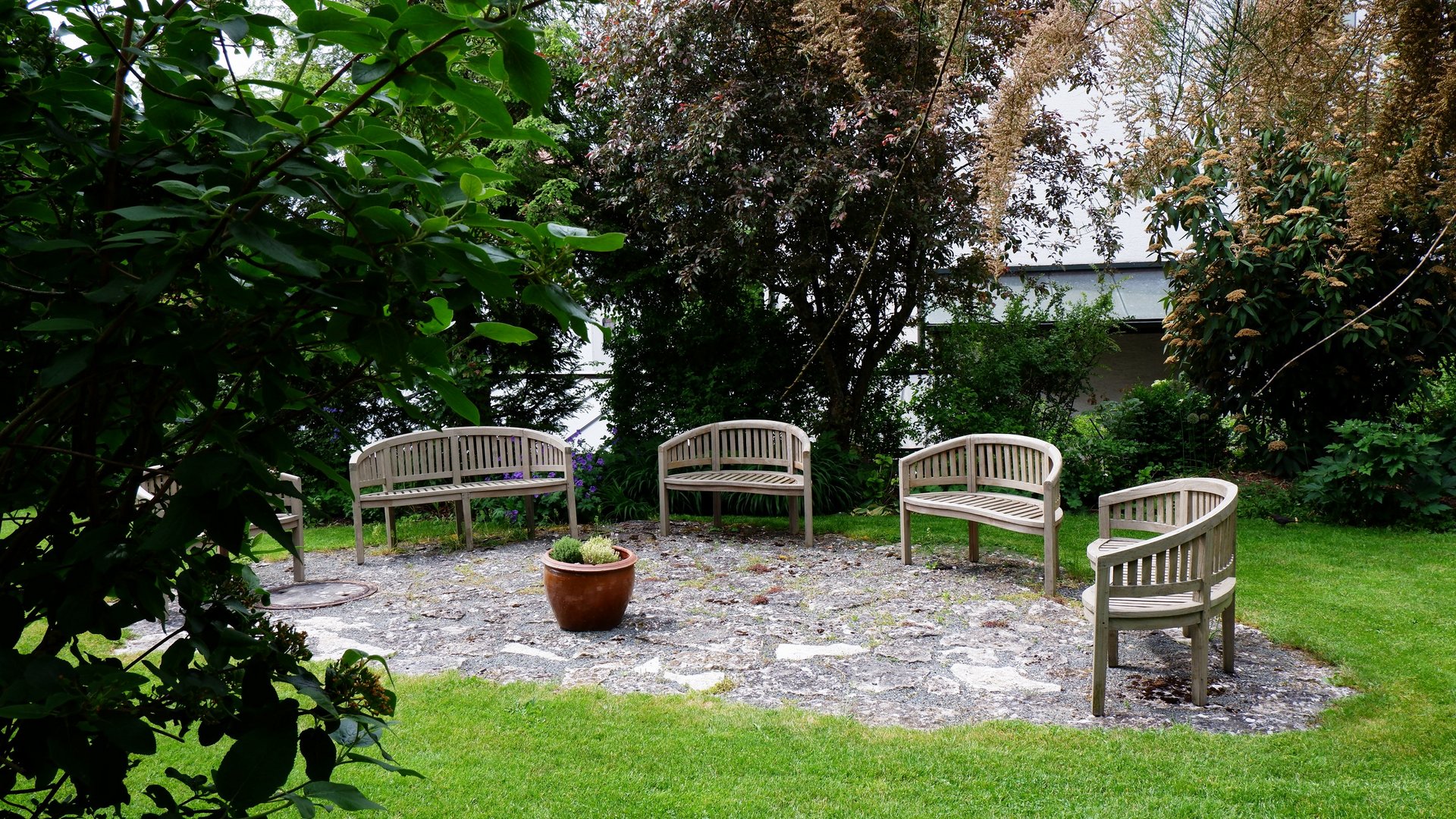Tagung mit Mehrwert Holzbänke im Kreis in einem Garten mit Rasen und Pflanzen