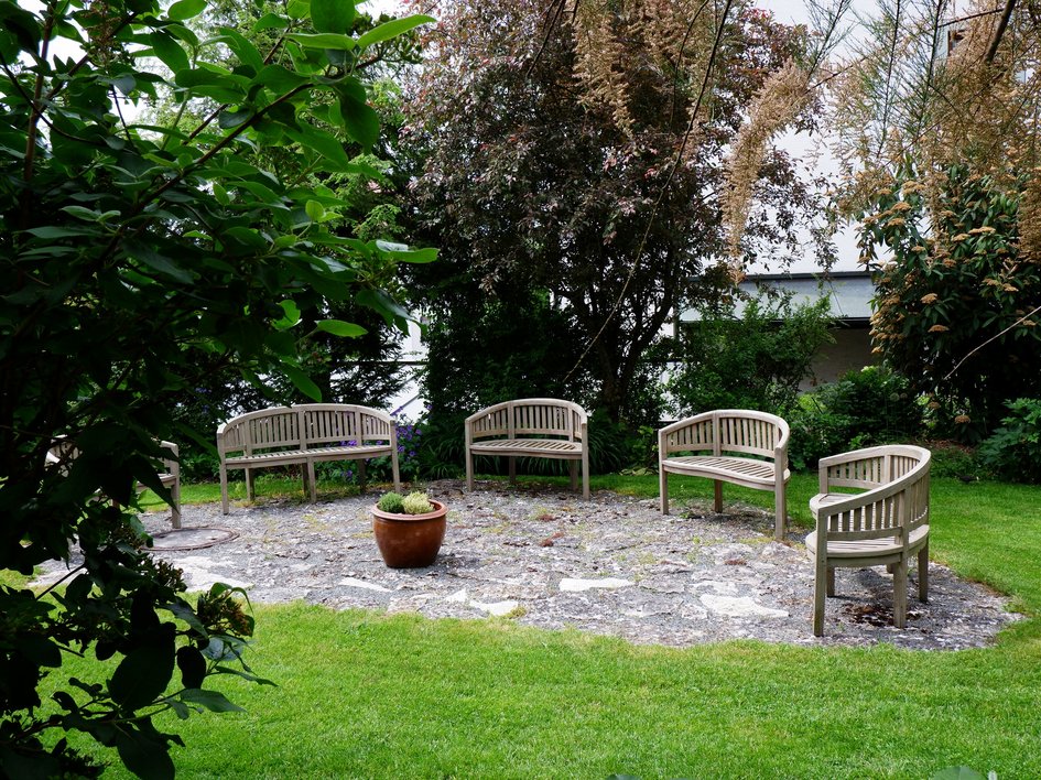 Tagung mit Mehrwert Holzbänke im Kreis in einem Garten mit Rasen und Pflanzen