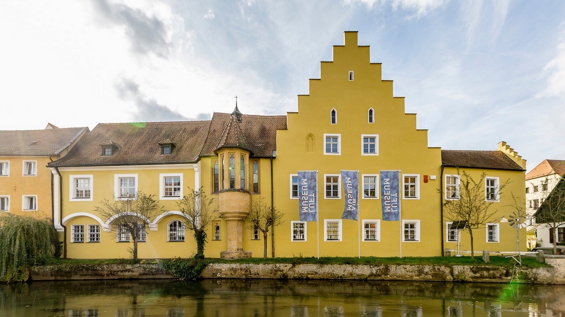 Hiking in Upper Palatinate: Active in nature Yellow historic building by water with stepped gable and flags