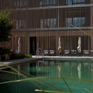 Angebote aus dem Romantik Hotel Hirschen Schwimmbad mit Liegestühlen vor modernem Holzgebäude bei Tageslicht