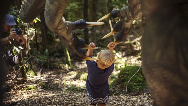Hotels in Regensburg und Umgebung: kultur-trächtig! Kind berührt die Krallen einer Dinosaurierfigur im Wald, Fotograf fotografiert daneben