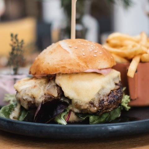 Gasthof Parsberg: Ein Gruß an den guten Geschmack Cheeseburger mit Salat und Pommes auf schwarzem Teller