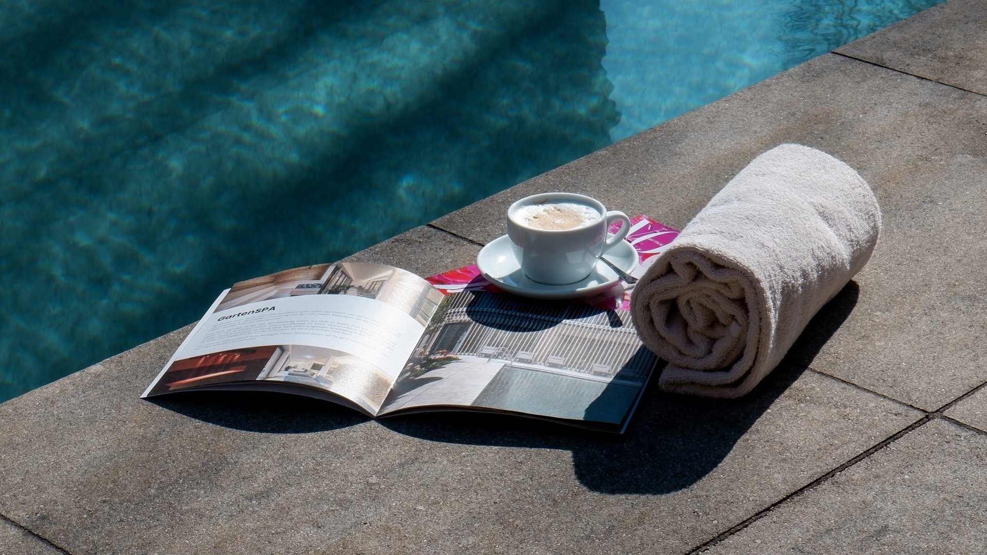 Day wellness in Upper Palatinate Rolled towel, cup of coffee, and magazine by the poolside