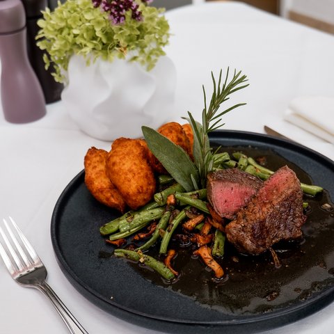 Guesthouse in Parsberg: A salute to great taste Beef steak with green beans and roasted potatoes on a black plate