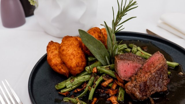 Hirschenblobb: unsere Bar Rindersteak mit grünen Bohnen und Bratkartoffeln auf schwarzem Teller
