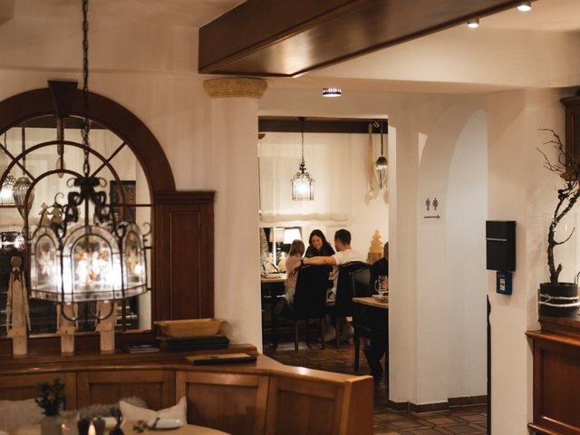 Romantik Hotel Hirschen: Bildergalerie Gemütliches Restaurant mit Holzdeko und Gästen am Esstisch im Hintergrund