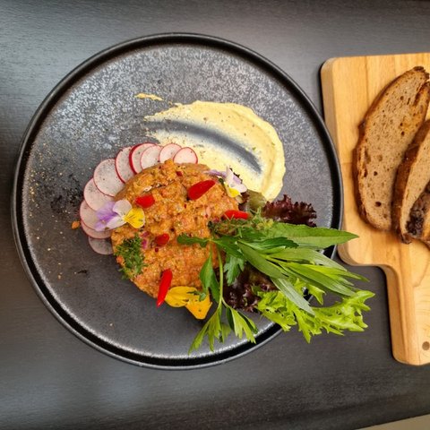 Beer garden in Parsberg: HirschenBlobb Beef tartare with radishes, salad, sauce and three bread slices on a wooden board