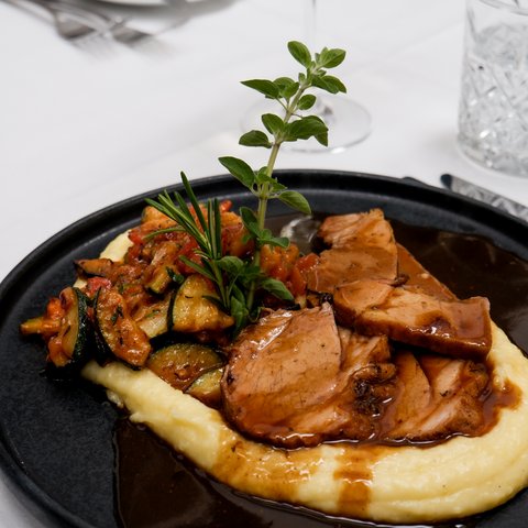 Kulinarik & Genuss in der Oberpfalz Schweinebraten mit Kartoffelpüree, Gemüse und dunkler Sauce garniert mit Kräutern